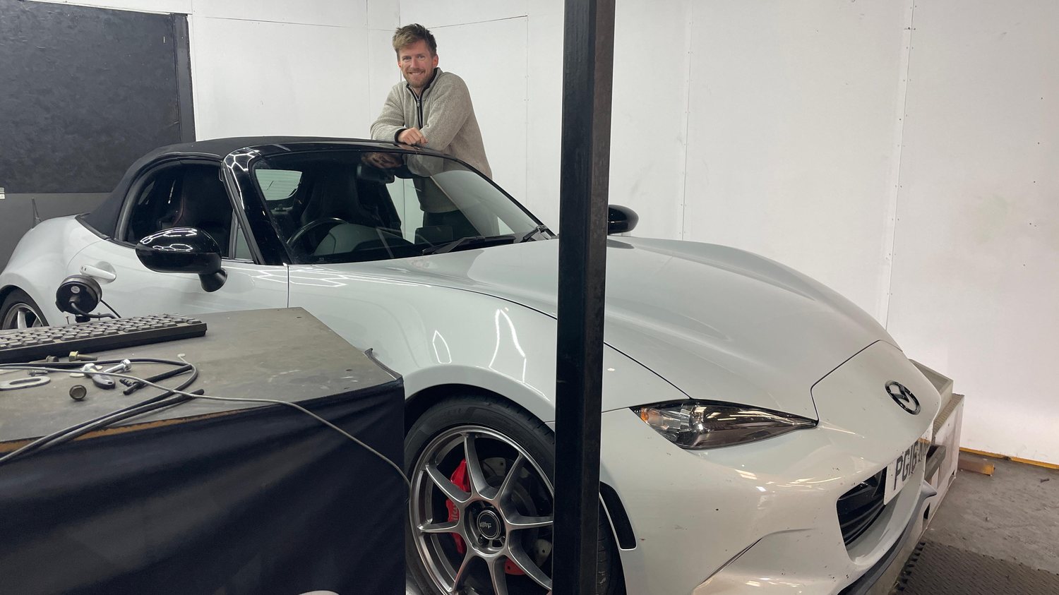 Aaron leaning on a Mazda MX-5 in the workshop