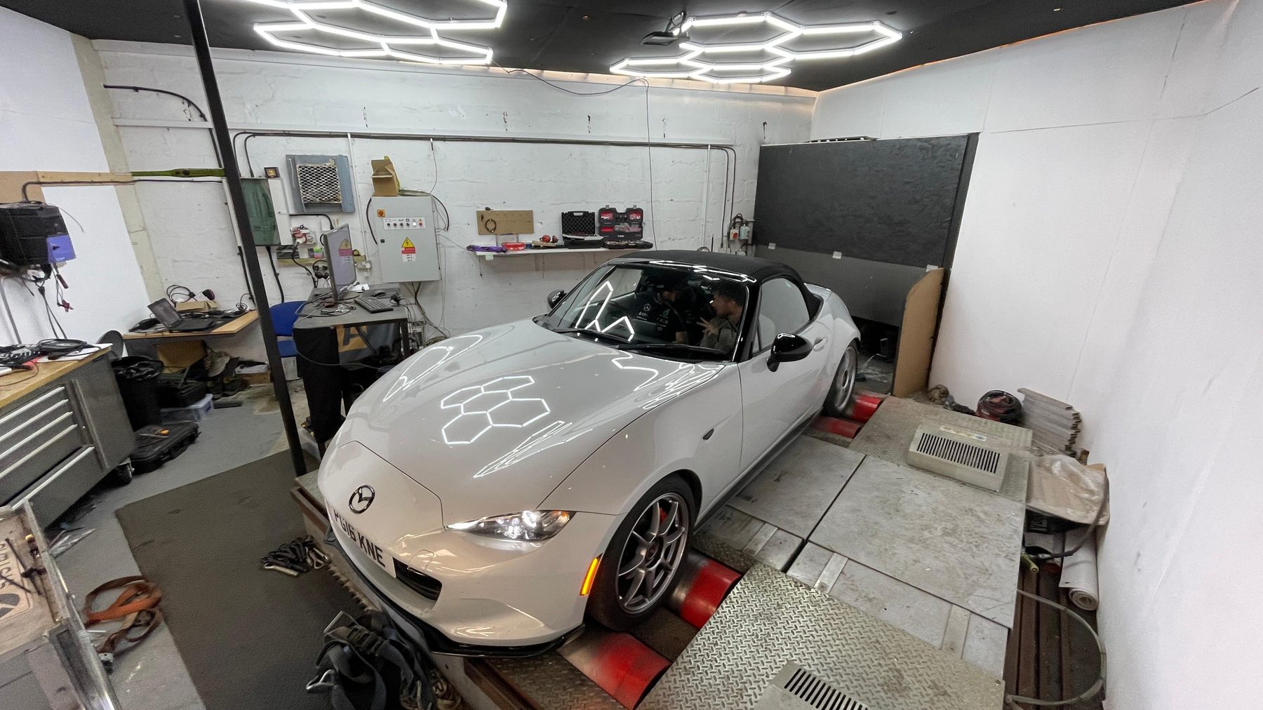A Mazda MX-5 strapped down on a rolling road in the workshop